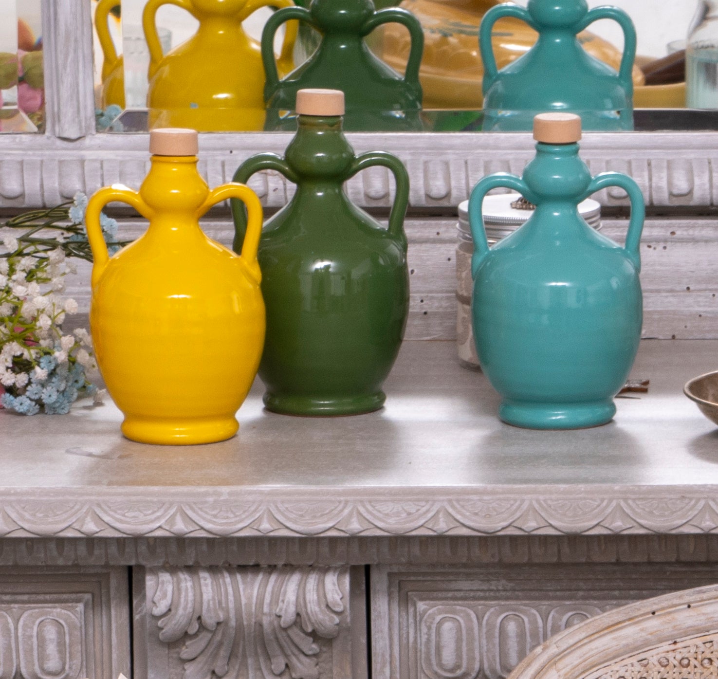 Bottiglie colorate di ceramica gialla, verde e turchese per Olio Extravergine di Oliva su tavolo vintage